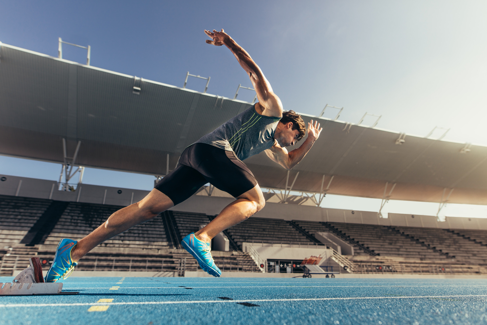Athlete using starting block to start his run on running track in a stadium.jpg